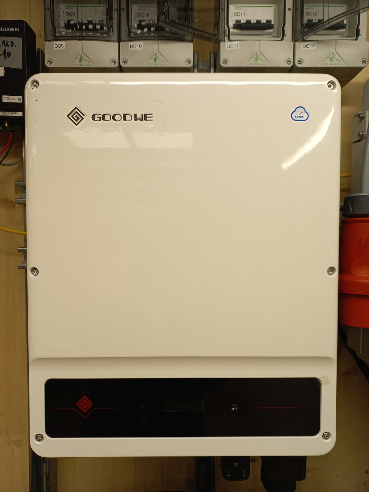 A white GoodWe grid-connected string inverter (exact model not identified) wall-mounted in a utility test bay in Bregenz, Austria